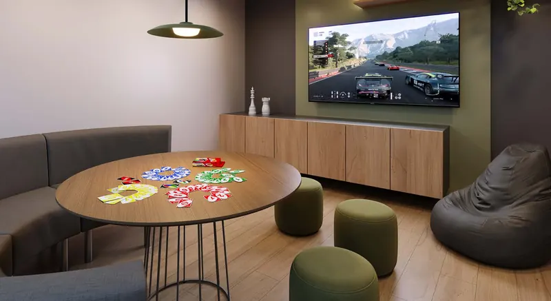 Sala de jogos do Dom Park Residencial com mesa redonda, TV e pufes